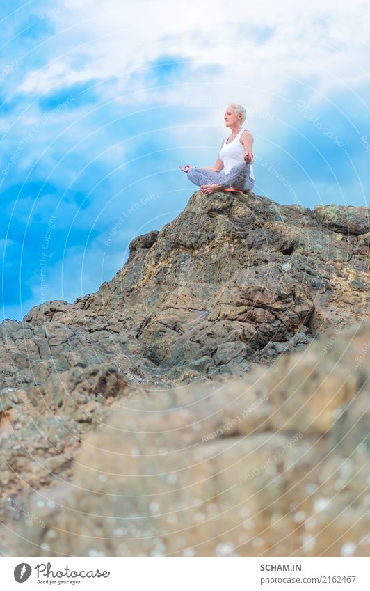 A beautiful mature aged woman sits on top of a cliff doing yoga. Meditation Yoga Feminine Woman Adults Female senior Grandmother Senior citizen 1 45 - 60 years