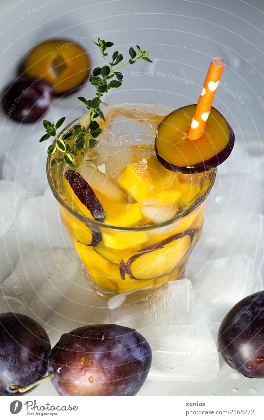 Iced soft drink with plum, mango, thyme, ice cubes and drinking straw Beverage Cold drink Plum Mango Thyme Ice cube Fruit Organic produce Vegetarian diet