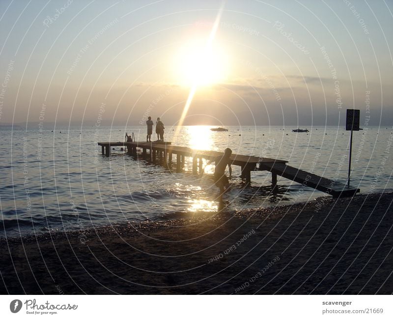 Sunset at Lake Garda Sunbeam White Light Evening sun Sunrise Dark Waves Watercraft Beach Footbridge Horizon Wood Romance Lighting Blue Bright Sky Orange