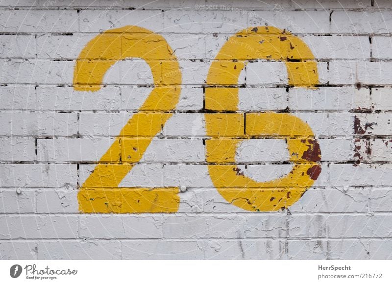 26 Manmade structures Wall (barrier) Wall (building) Brick Digits and numbers Yellow White Dye Paintwork Flake off Furrow Colour photo Exterior shot
