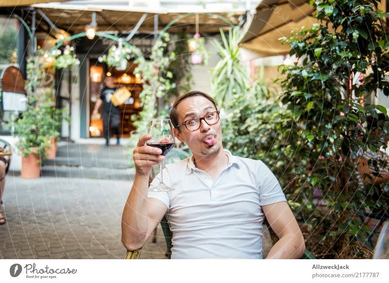 Man with wine glass sticks out his tongue 1 Person Young man Sit Day Exterior shot Warmth Summer Wine Wine glass Red wine Alcoholic drinks Drinking Toast