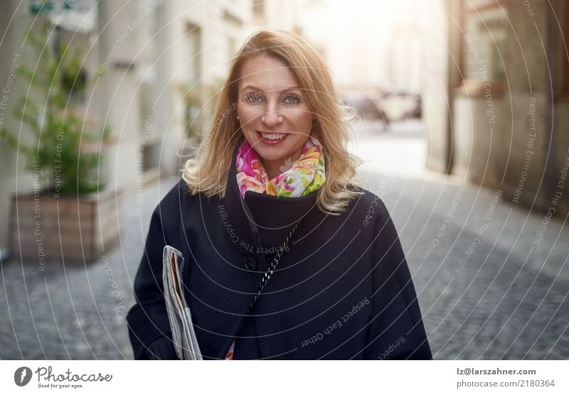 Blond mature smiling woman on street Elegant Happy Face Business Woman Adults 1 Human being 30 - 45 years Newspaper Magazine Pedestrian Street Coat Blonde
