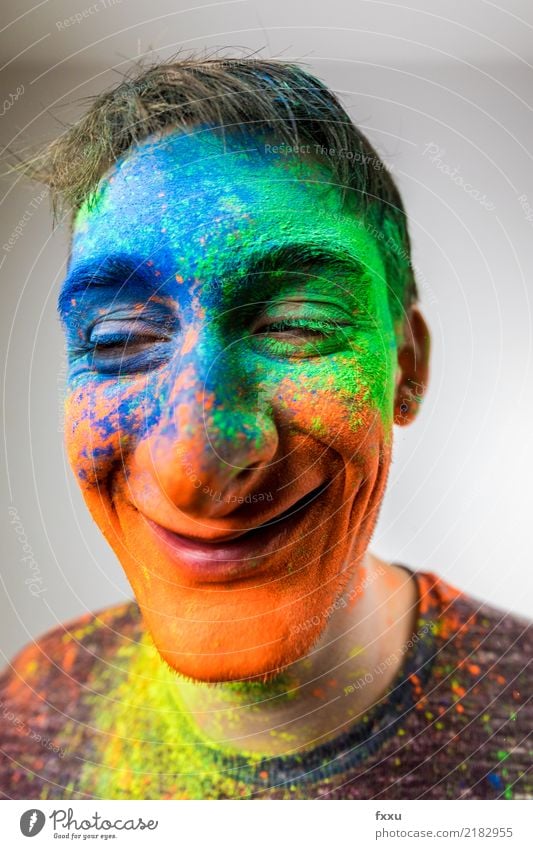 Man with Holi powder in face cartoon Multicoloured Laughter Smiling Crazy Perspective Holi Kino Powder Young man Face Blue Yellow Green Orange Nose Large