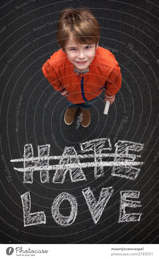 Boy with chalk doesn't want hate but love Human being Masculine Child Boy (child) Infancy Life 1 3 - 8 years Street Jeans Chalk Chalk drawing Smiling Love Write