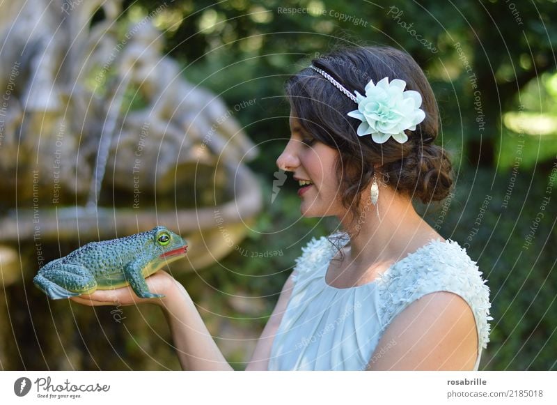 kiss me .... young brunette woman dressed like a princess looks skeptically at a frog on her hand and considers whether to kiss it Young woman Stage play