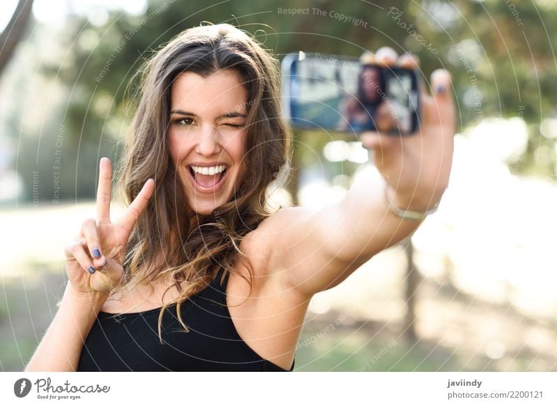 young woman selfie in the park with a smartphone doing v sign Joy Happy Beautiful Face Cellphone Camera Technology Human being Woman Adults Hand Fingers Smiling
