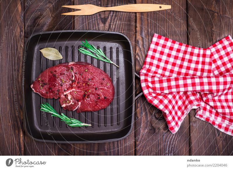 Slices of medium rare roast beef meat on wooden cutting board, pepper and  rosemary branches on wooden background. Top view. Gourmet food. Raw meat  beef steak. Stock Photo