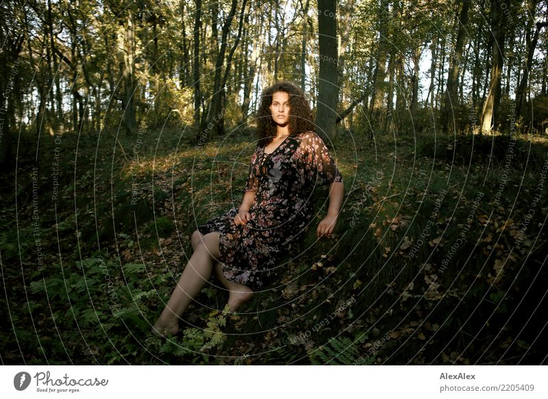 Young beautiful tall woman sitting barefoot on the ground in the forest looking at the camera against the sun pretty Life Well-being Young woman