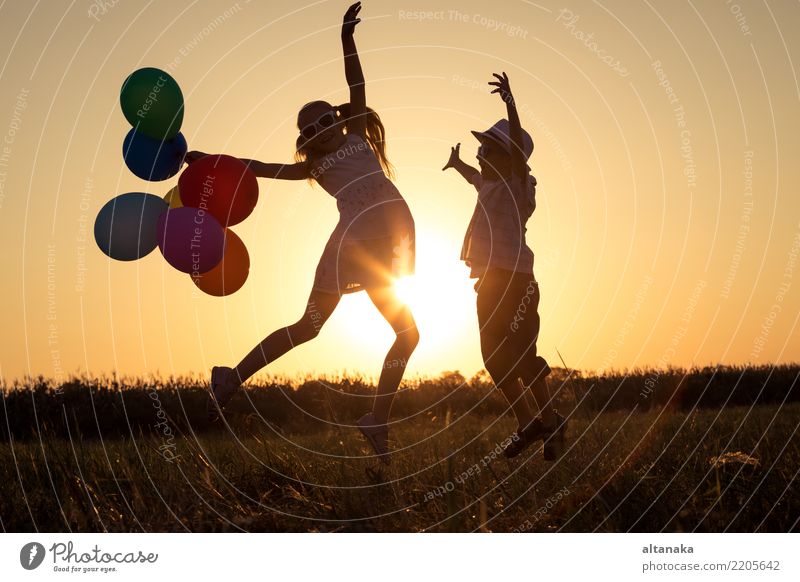 Silhouette of two happy children which playing on the field at the sunset time. They having fun on the nature. Lifestyle Joy Happy Leisure and hobbies Playing