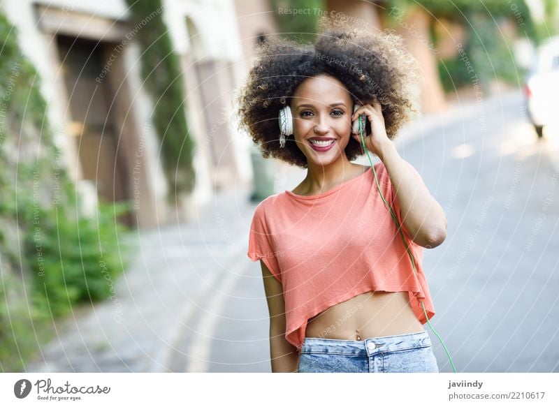Portrait of young attractive black girl in urban background listening to the music with headphones. Lifestyle Joy Happy Beautiful Hair and hairstyles Face