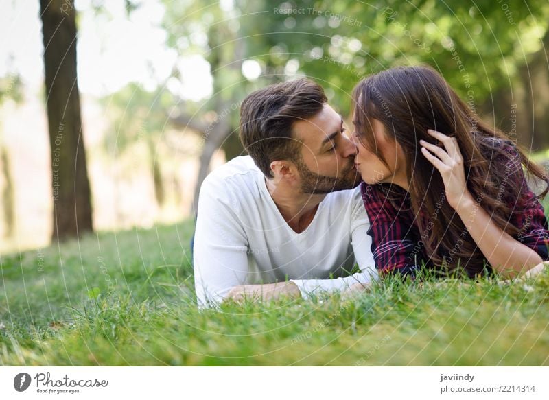 Beautiful young couple kissing on grass in an urban park Lifestyle Joy Happy Summer Woman Adults Man Couple 18 - 30 years Youth (Young adults) 30 - 45 years