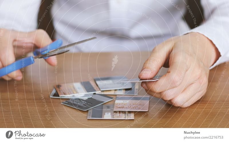 Hand cutting credit card with scissors on table Table Economy Financial Industry Financial institution Scissors Woman Adults Man Fingers Plastic Poverty Safety