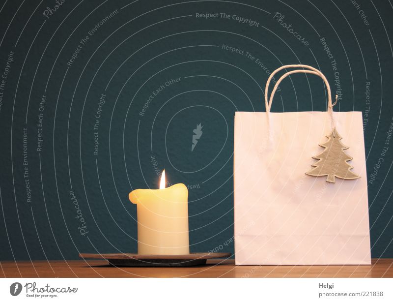 Paper bag with wooden fir tree as decoration and burning candle standing on a table in front of a dark blue background Design Decoration Packaging