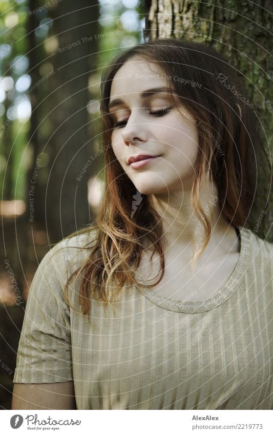 Natural portrait of a young athletic woman in the forest leaning against a tree and looking down pretty Contentment Senses Young woman Youth (Young adults) Face