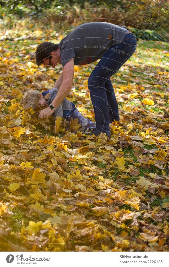 Man plays with child in autumn leaves Shallow depth of field blurriness Sunlight Day Copy Space left Exterior shot Colour photo Movement