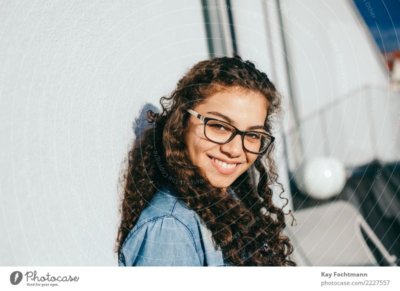 Smiling woman with curly hair and glasses leaning against the house wall Lifestyle Joy Happy Beautiful Hair and hairstyles Well-being Contentment Feminine