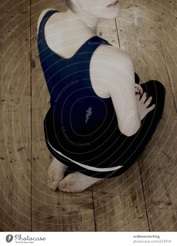 Female figure squatting on a wooden floor with her back to the viewer; desaturated colors. Only the mouth of the face is indicated Yoga Young woman