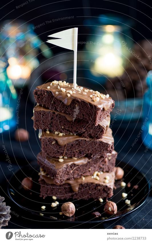 piled up chocolate cake with hazelnut and flag on a black plate with blue lights in the background Cake Chocolate brownie Chocolate cake Hazelnut hazelnut cream