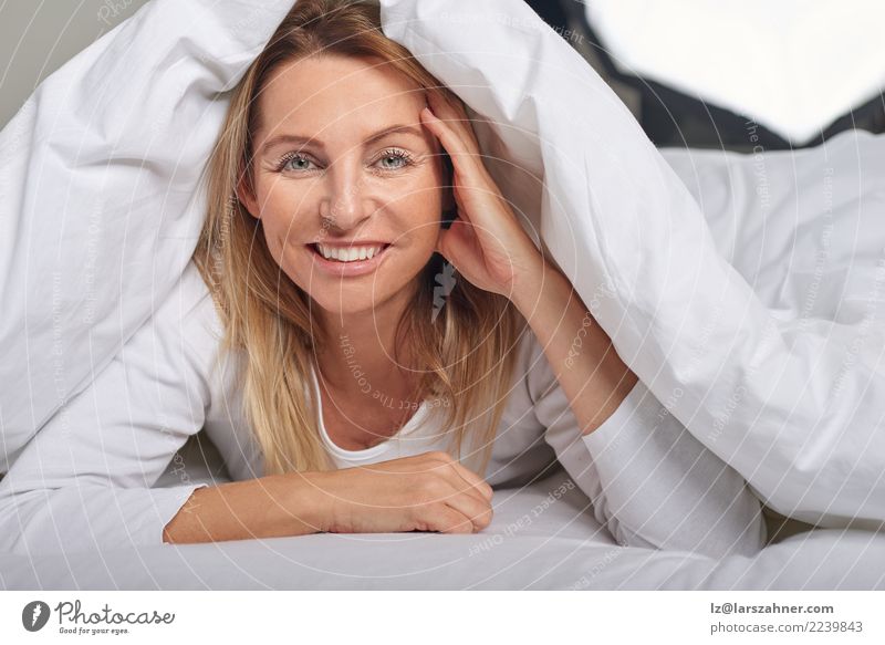 Beautiful middle-aged woman under sheets - a Royalty Free Stock