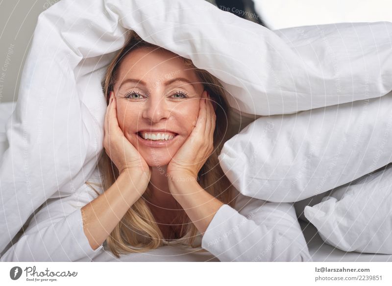 Beautiful middle-aged woman under sheets Happy Skin Face Relaxation Bedroom Woman Adults 1 Human being 45 - 60 years Blonde Smiling Sleep Happiness Under Soft