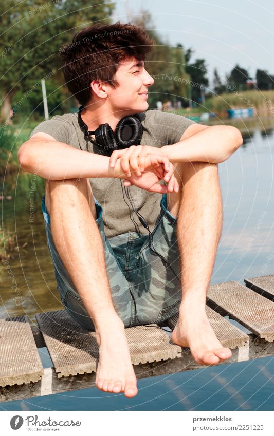 Young smiling boy sitting on jetty over the lake Lifestyle Joy Happy Relaxation Leisure and hobbies Vacation & Travel Summer Summer vacation Human being