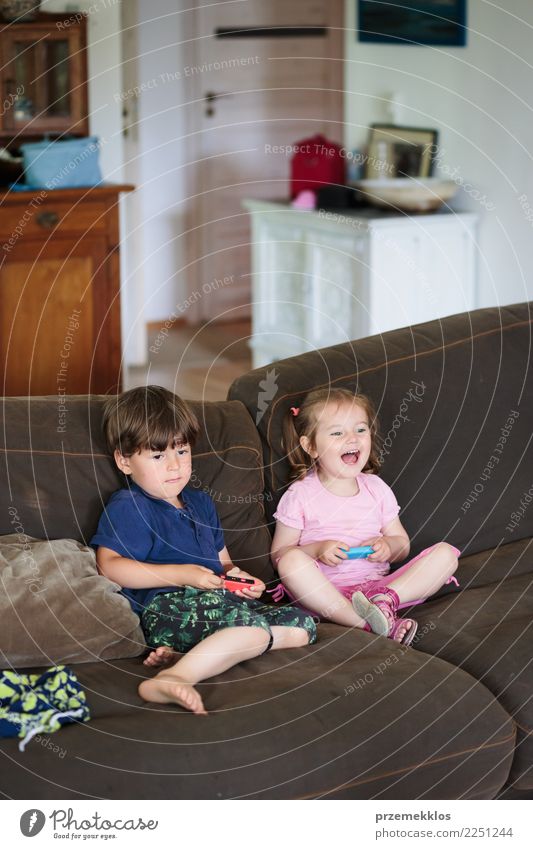 Kids playing video game sitting on sofa at home Lifestyle Joy Happy Leisure and hobbies Playing Living or residing Sofa Child Technology Toddler Girl