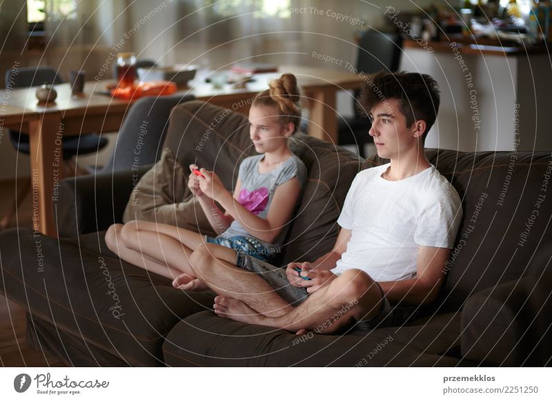 Concentrated young boy and girl playing video games sitting on sofa at home Lifestyle Joy Leisure and hobbies Playing Sofa Child Technology Girl Boy (child)