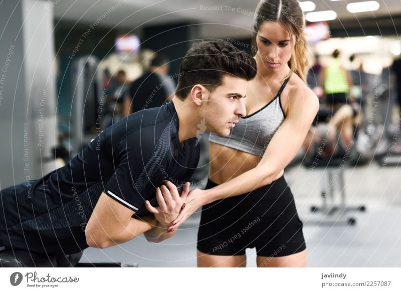 Female personal trainer helping a young man lift weights Lifestyle Body Sports Human being Masculine Feminine Young woman Youth (Young adults) Young man Woman