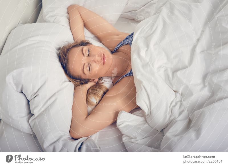 A young attractive girl in striped pajamas is lying in bed in her