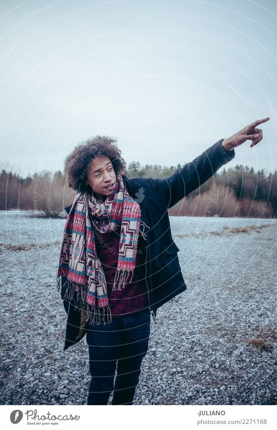 Young man with winter clothing pointing in direction - a Royalty