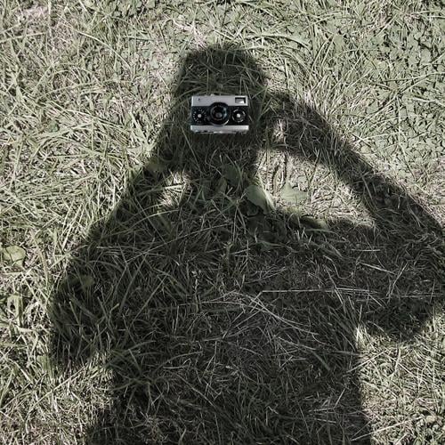 view into the camera Camera Masculine 1 Human being Grass Meadow Gray Green Take a photo Exterior shot Close-up Day Shadow Contrast Upper body