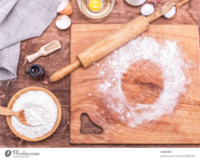 Cooking tools and ingredients flat lay with copy space. Baking header with measuring  spoons, wooden scoops, whisks, rolling pin, cookie cutters, sugar, flour,  eggs and cinnamon on a blue background. Stock Photo