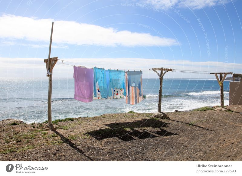 Colorful laundry hangs to dry in the sea breeze Fragrance Ocean Waves Laundry clothesline Landscape Earth Water Sky Clouds Rock coast Fishing village Clothing