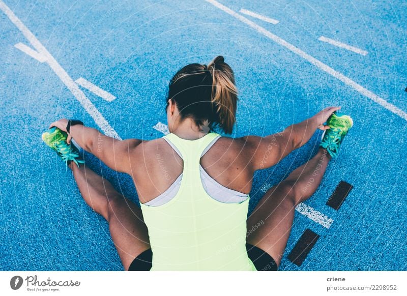 Fit Woman stretching on blue running track before run Lifestyle Sports Track and Field Success Jogging Stadium Racecourse Human being Adults Competition legs