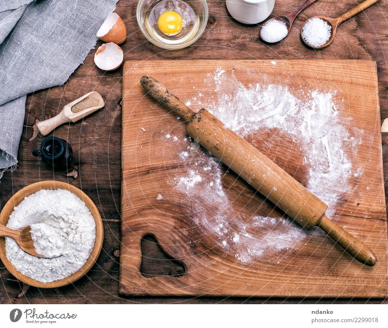 Cooking tools and ingredients flat lay with copy space. Baking header with measuring  spoons, wooden scoops, whisks, rolling pin, cookie cutters, sugar, flour,  eggs and cinnamon on a blue background. Stock Photo