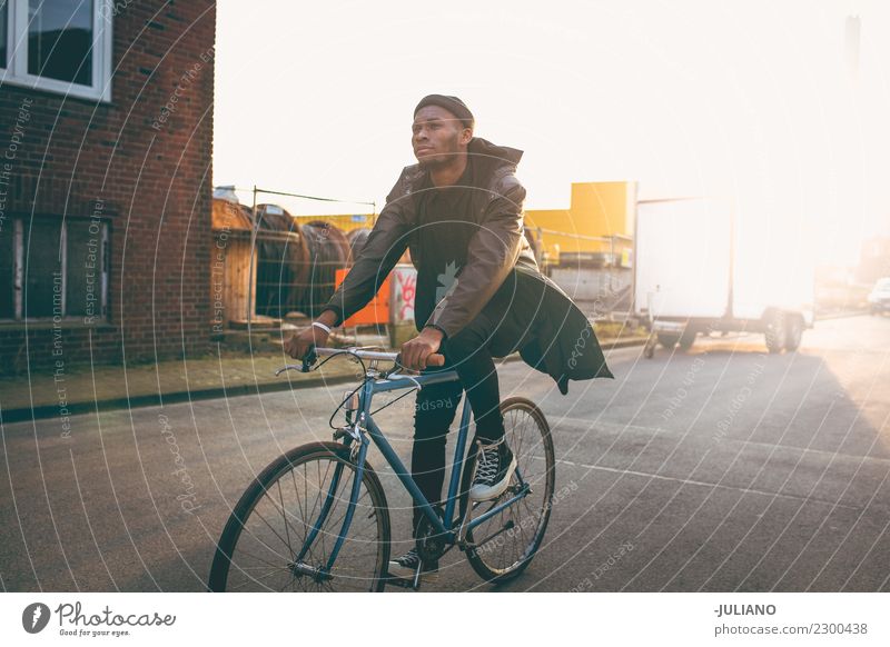 Young modern hipster riding bike trough urban city while sunset Modern Town City life Lifestyle Freedom Sunset Dusk Sneakers Transport Hipster Clothing Jacket