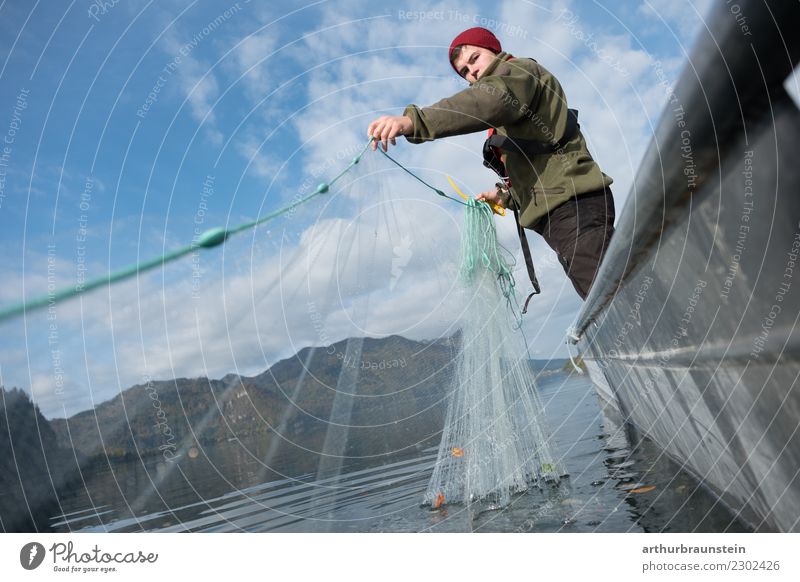 Young fisherman in a fishing boat at the lake catches up with his fishing net Food Fish Nutrition Slow food Healthy Eating Leisure and hobbies Fishing (Angle)