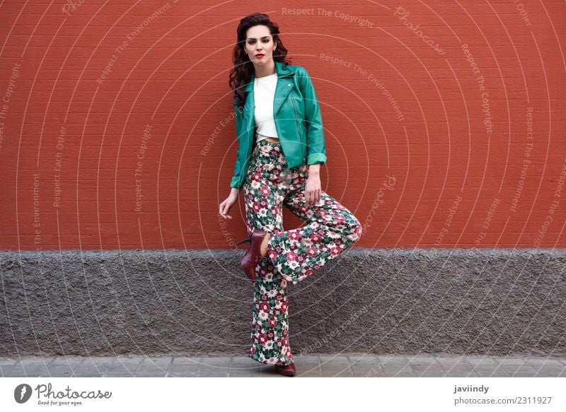 Young brunette woman, model of fashion, wearing green modern jacket and flower pants on red wall Lifestyle Style Beautiful Hair and hairstyles Face Human being