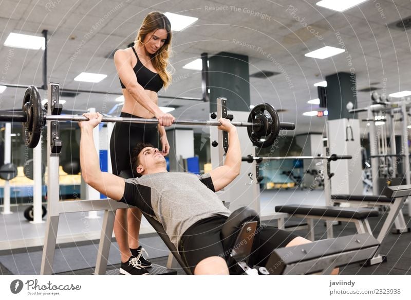 Female personal trainer helping a young man lift weights Lifestyle Body Sports Human being Young woman Youth (Young adults) Young man Woman Adults Man 2