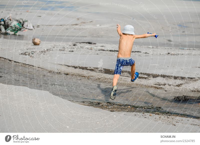 Seven years old boy jumping over the small river Lifestyle Joy Playing Summer Ocean Island Human being Child Boy (child) Infancy 1 3 - 8 years Landscape Hat