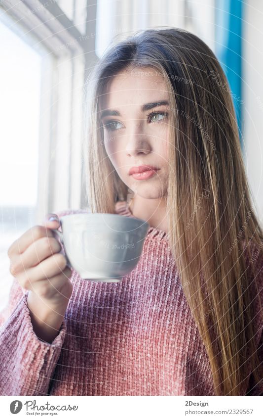 Pensive woman looking through a window Hot drink Tea Lifestyle Beautiful Face Relaxation Calm Meditation Winter House (Residential Structure) Human being Woman