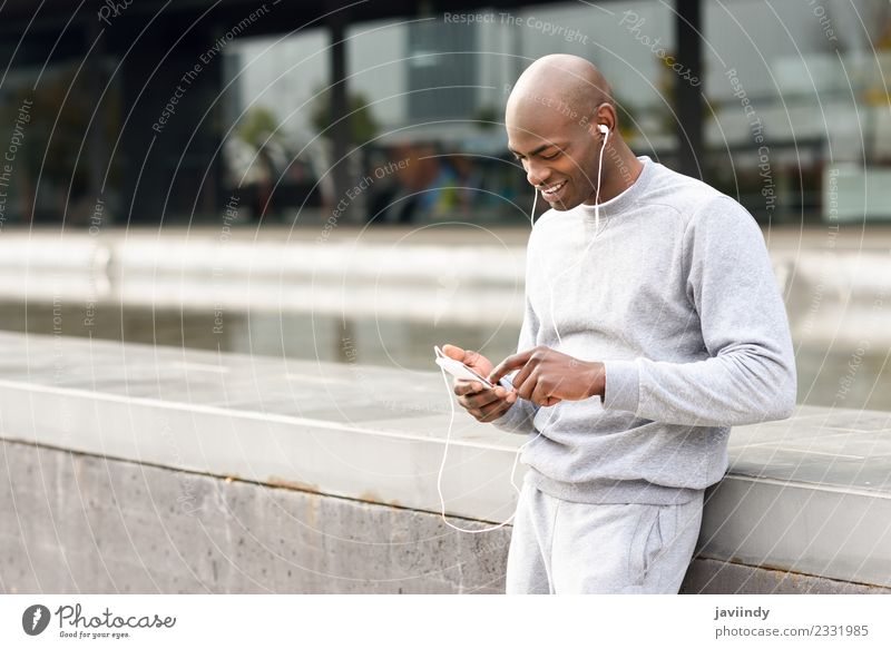 Attractive black man listening to music with headphones in urban background Lifestyle Happy Music Sports Telephone PDA Technology Human being Masculine