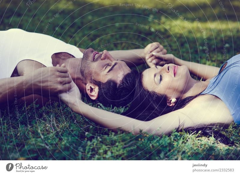 Happy smiling couple laying on green grass in a beautiful park Lifestyle Joy Relaxation Leisure and hobbies Human being Young woman Youth (Young adults)