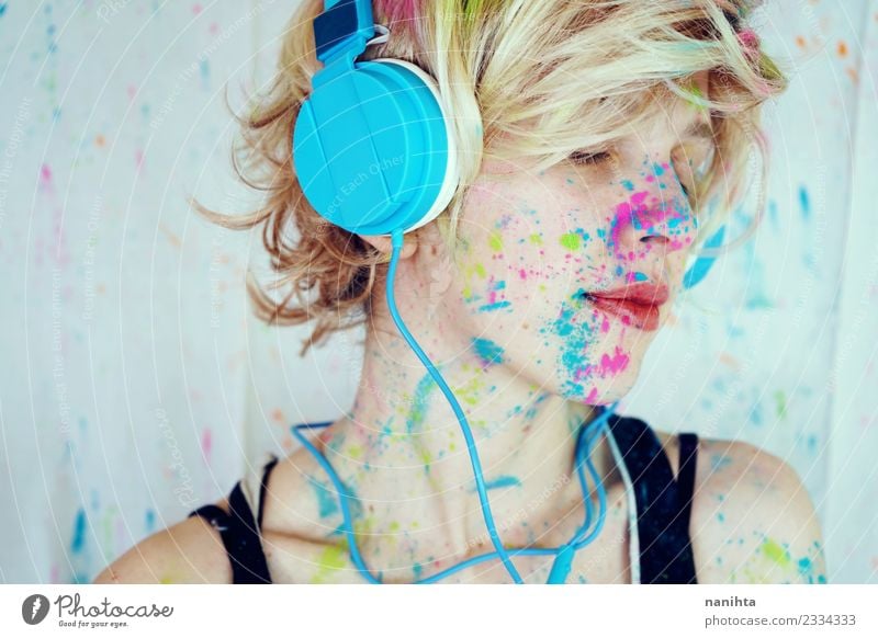 Young woman with paint in her face is listening to music Lifestyle Style Design Exotic Relaxation Calm Leisure and hobbies Technology Entertainment electronics