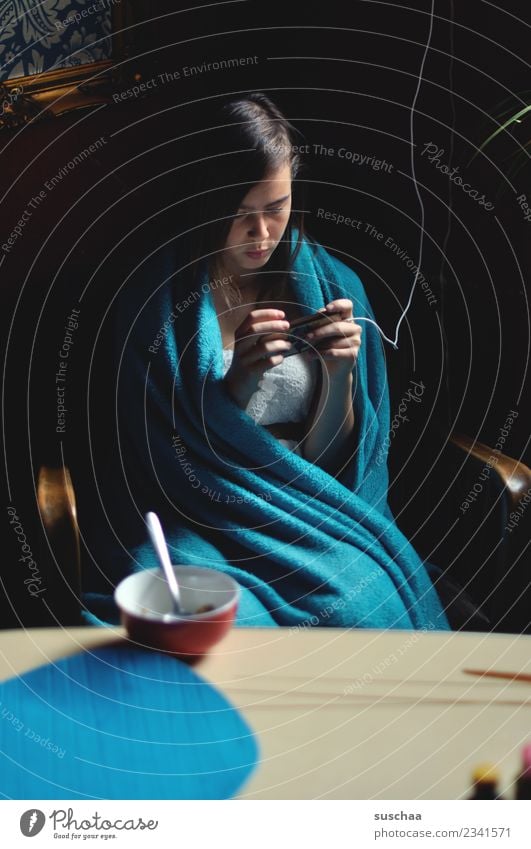 teenager sits at the breakfast table wrapped in a blanket and looks into her smartphone girl Child Youth (Young adults) Young woman 13 - 18 years Internet