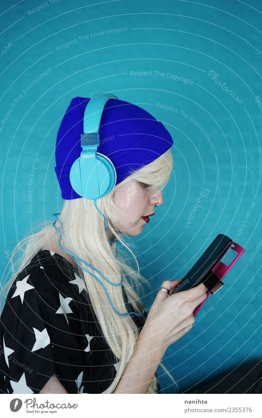 Young woman listening to music with her headphones and phone Lifestyle Style Design Hair and hairstyles Leisure and hobbies Cellphone MP3 player Technology