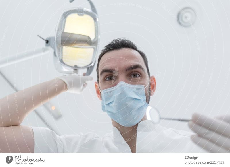 Dentist leaned over patient in dentist's chair at clinic. Health care Medical treatment Medication Profession Doctor Tool Human being Masculine Young man