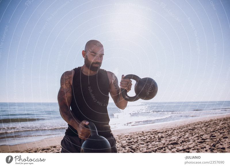 Sports man is doing kettle bells workout at the beach Young man Beach Fitness Sports Training Professional training Hard Perspire Musculature Joy Sportsperson