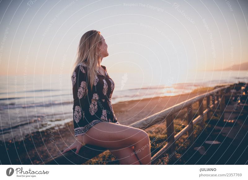 Young woman sitting on railing watching the sunset at the ocean Sun Beach Blonde Cool (slang) Dusk Joy Girl Good Goodness Laughter Lifestyle Ocean Retro Sand