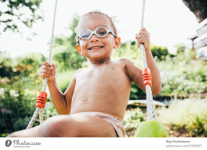 Cute black boy having fun on a swing in his parents garden Lifestyle Joy Summer Human being Toddler Boy (child) Family & Relations Infancy 1 1 - 3 years
